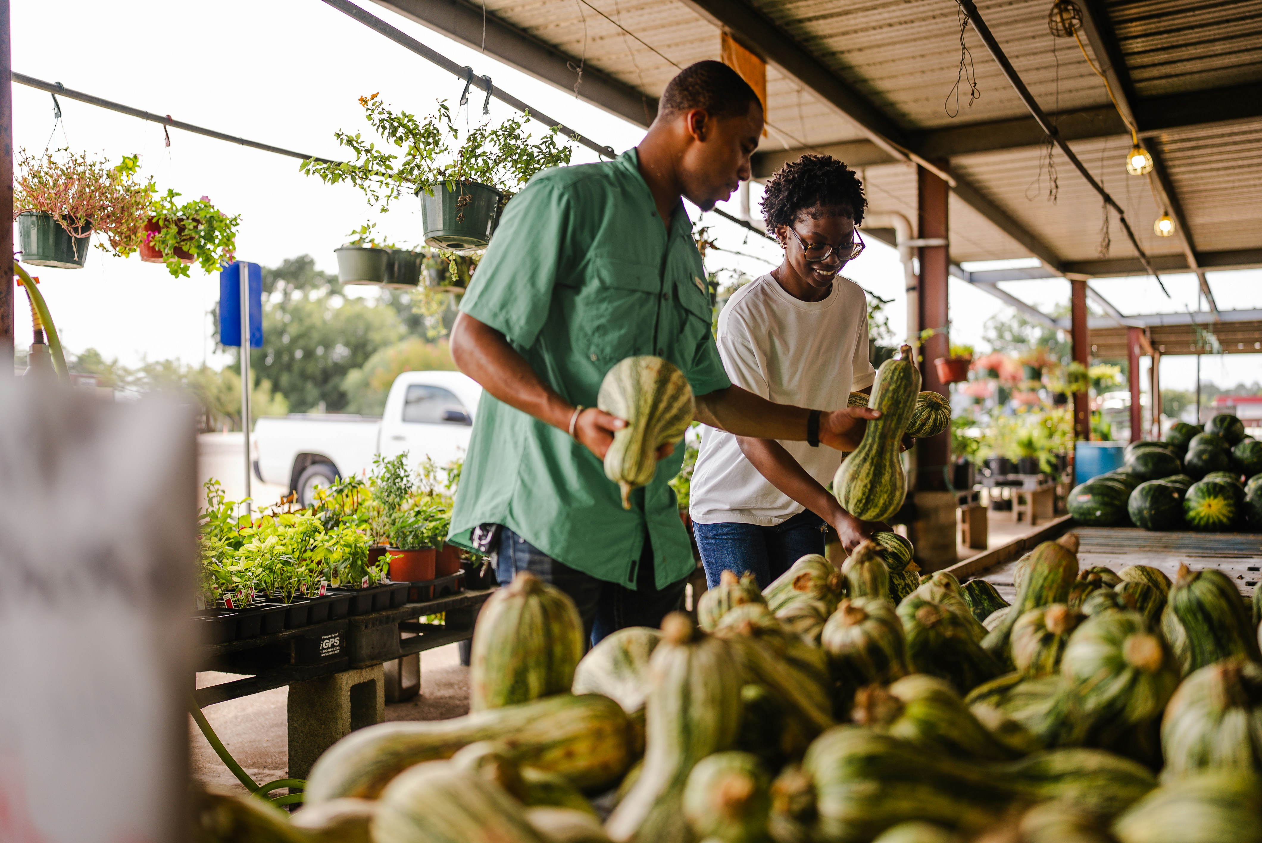 Two people selecting produce at a farmers market
